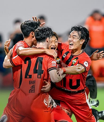 Gangwon FC players celebrating in match kits on the pitch.