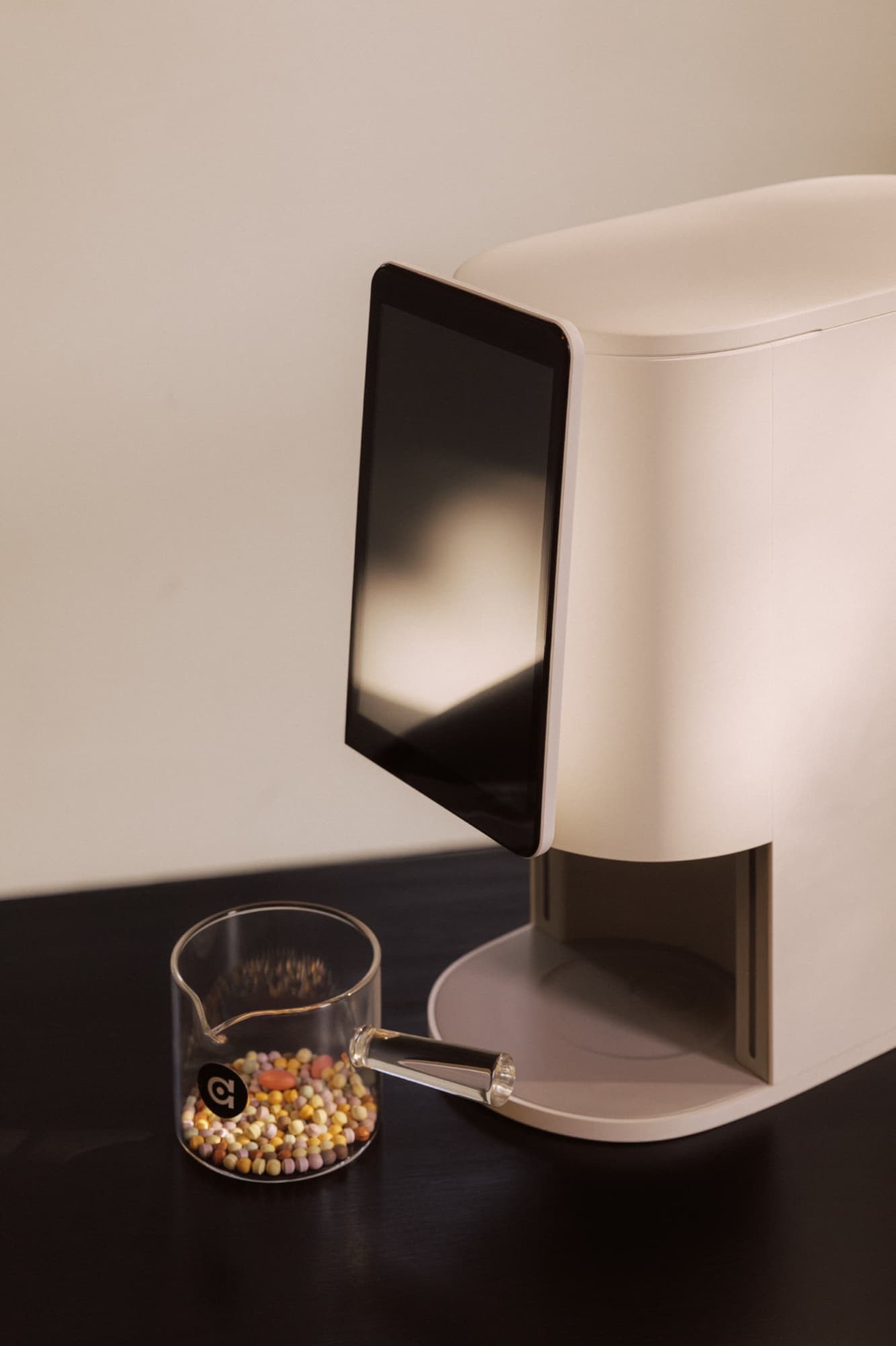 Close-up of the E1 tablet display beside a glass cup of colored beads — today's personalized mix.