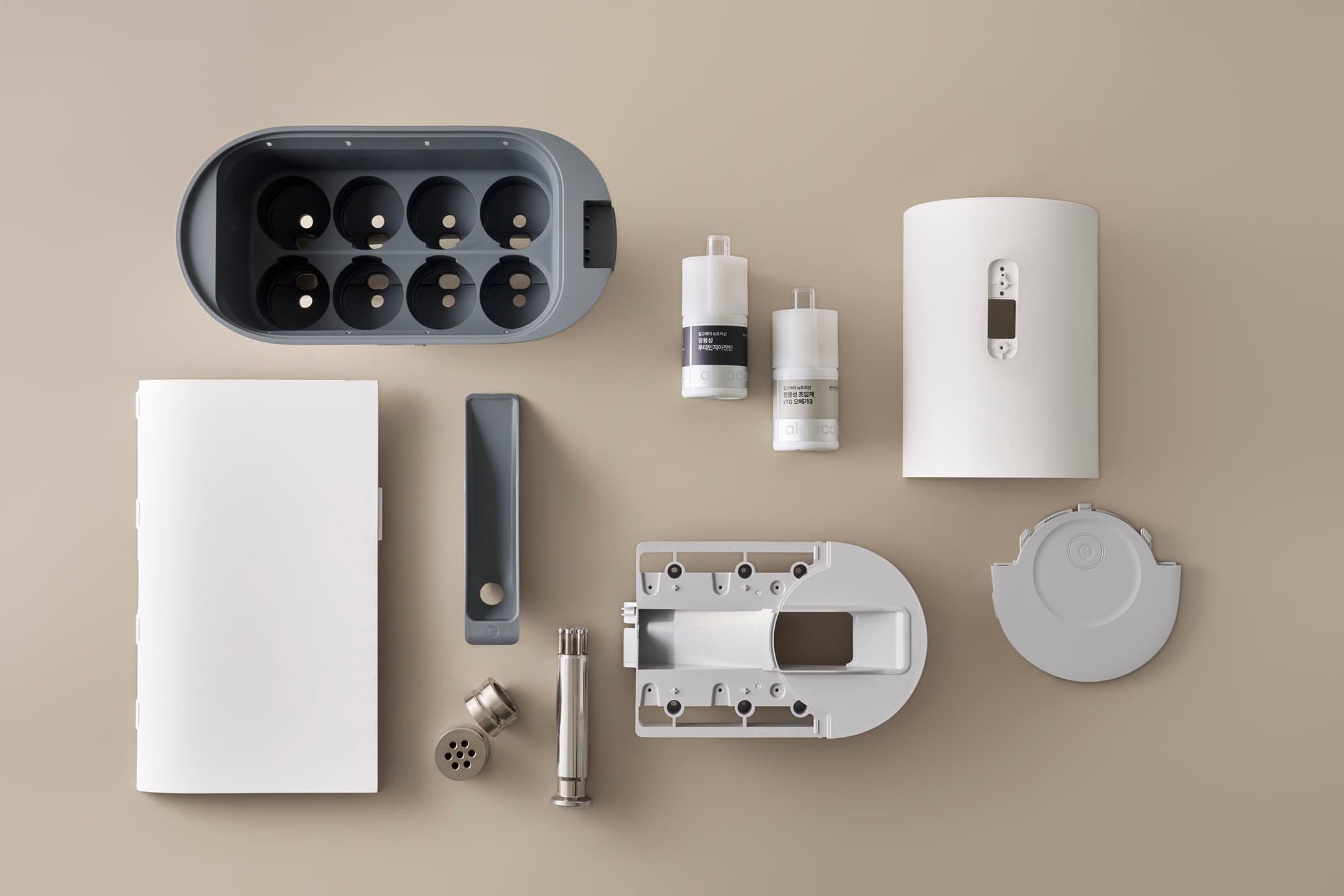 Component flat-lay — cartridges, internal modules, and the dispenser housing arranged as a palette.